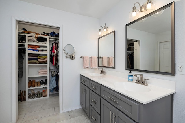 bathroom featuring a spacious closet, double vanity, and a sink