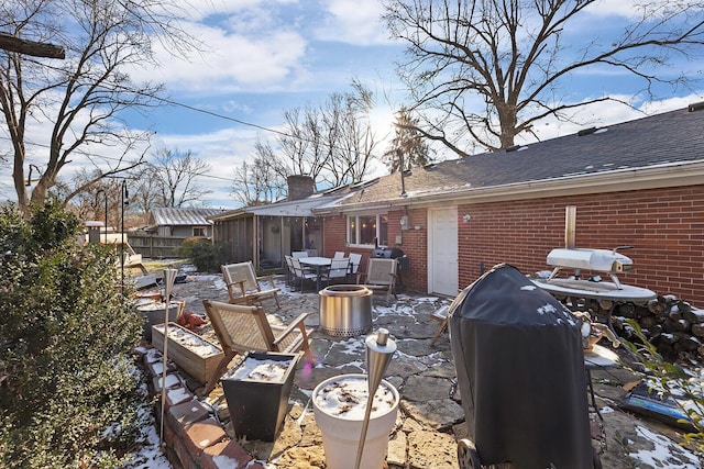 exterior space featuring a shingled roof, brick siding, and a chimney