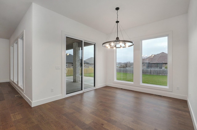 unfurnished dining area with a notable chandelier, dark hardwood / wood-style flooring, and a healthy amount of sunlight