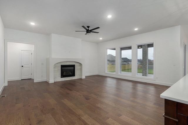 unfurnished living room with ceiling fan, dark wood-type flooring, and a fireplace