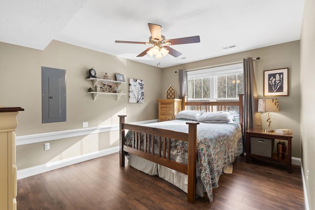 bedroom featuring ceiling fan, electric panel, and dark hardwood / wood-style floors