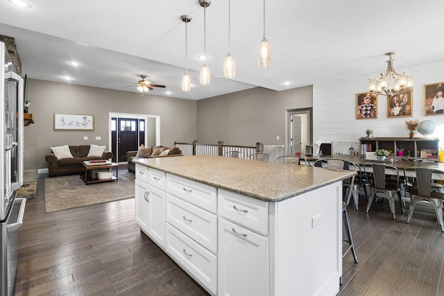 kitchen with pendant lighting, white cabinetry, a kitchen bar, and a kitchen island