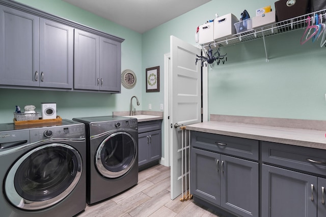 washroom with cabinets, washer and clothes dryer, and sink