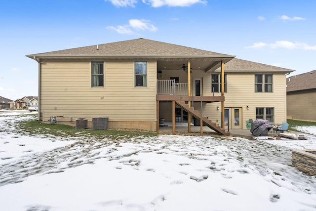 snow covered back of property with ceiling fan, a balcony, and central air condition unit