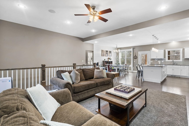 living room featuring sink and ceiling fan with notable chandelier