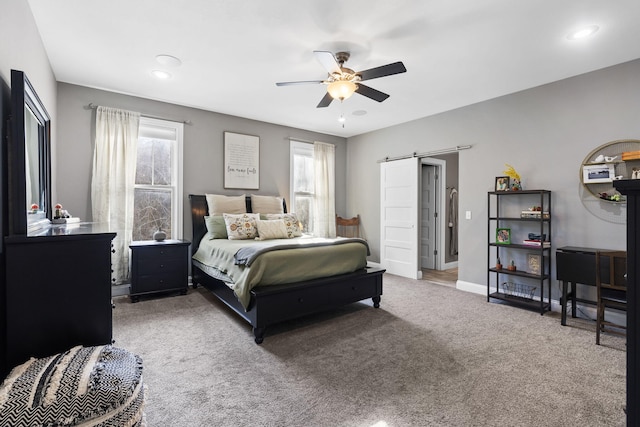 bedroom featuring ceiling fan, multiple windows, a barn door, and carpet