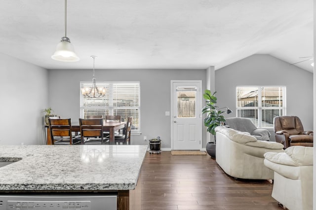 living room with an inviting chandelier, vaulted ceiling, a healthy amount of sunlight, and dark hardwood / wood-style floors