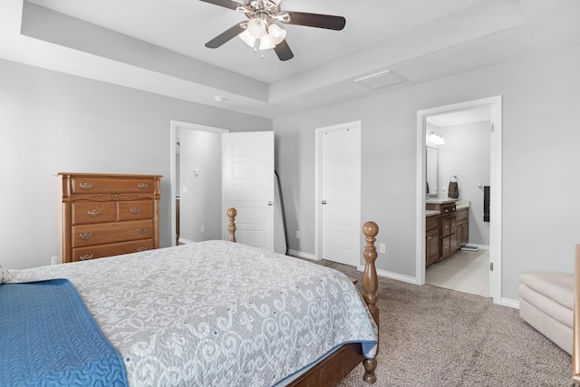 carpeted bedroom featuring ensuite bathroom, a raised ceiling, and ceiling fan