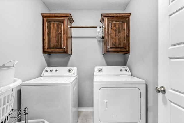 laundry room featuring a textured ceiling, washing machine and dryer, and cabinets