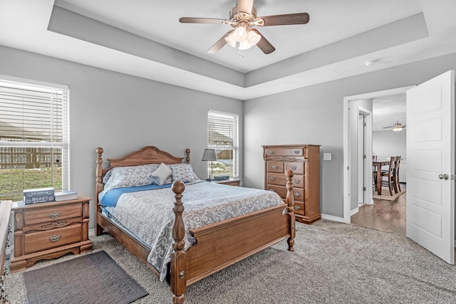 bedroom featuring ceiling fan, a raised ceiling, and carpet