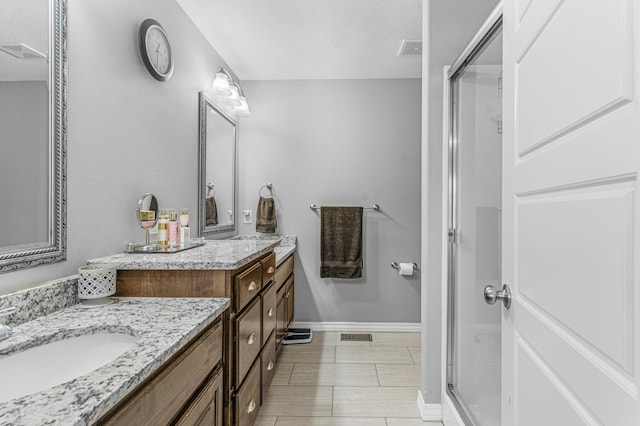 bathroom with a shower with door, vanity, and a textured ceiling