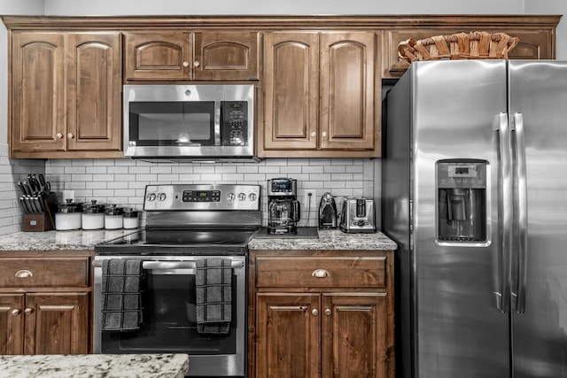 kitchen with tasteful backsplash, light stone counters, and appliances with stainless steel finishes