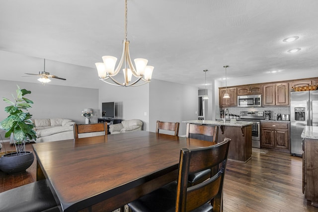 dining room featuring sink, dark wood-type flooring, and ceiling fan with notable chandelier