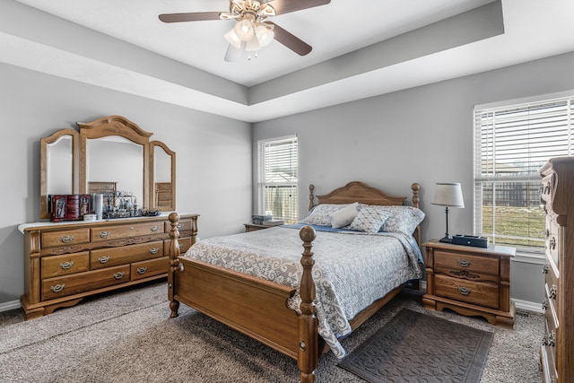 bedroom with a raised ceiling, carpet floors, and ceiling fan