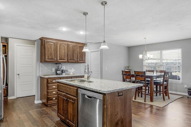 kitchen with an island with sink, decorative light fixtures, stainless steel dishwasher, and tasteful backsplash