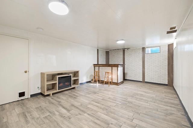 basement featuring brick wall and light wood-type flooring