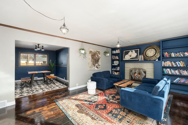 living room with wood-type flooring, a fireplace, ornamental molding, and built in shelves