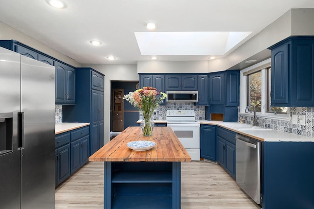 kitchen with blue cabinets, appliances with stainless steel finishes, and a skylight