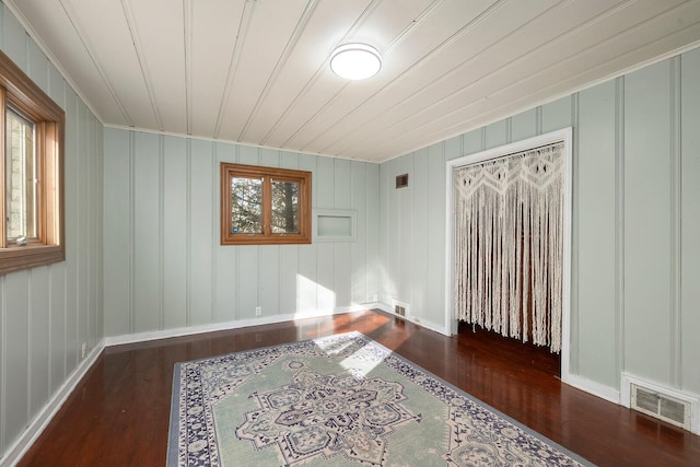 empty room with dark wood-type flooring and a wealth of natural light