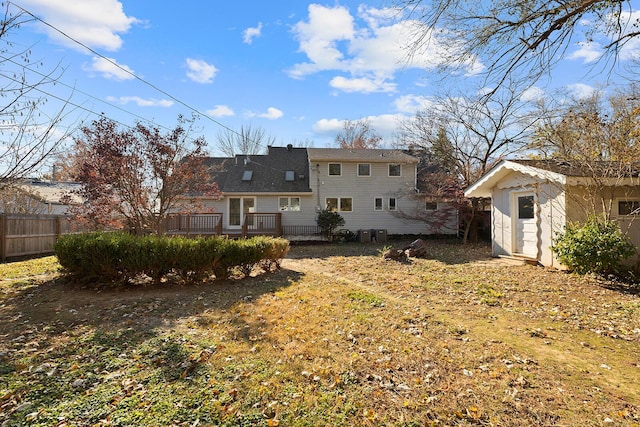 back of property featuring a lawn, a deck, and a storage shed