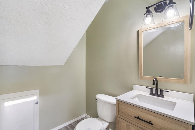 bathroom featuring wood-type flooring, toilet, vanity, and lofted ceiling