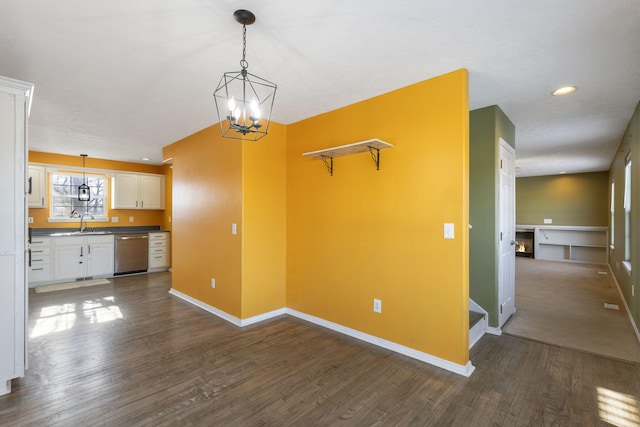 unfurnished living room featuring dark wood-type flooring, a chandelier, and sink