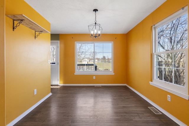 unfurnished dining area featuring a chandelier and dark hardwood / wood-style flooring