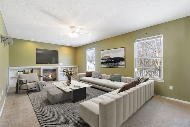 living room with a textured ceiling, ceiling fan, a healthy amount of sunlight, and light colored carpet