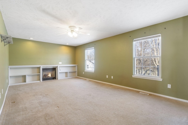 unfurnished living room with a textured ceiling, ceiling fan, and carpet