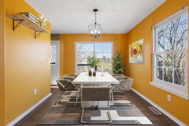 dining area featuring dark hardwood / wood-style floors, a notable chandelier, and a healthy amount of sunlight