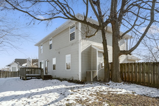 snow covered back of property featuring a wooden deck