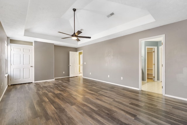 unfurnished bedroom with dark hardwood / wood-style floors, a raised ceiling, and ceiling fan