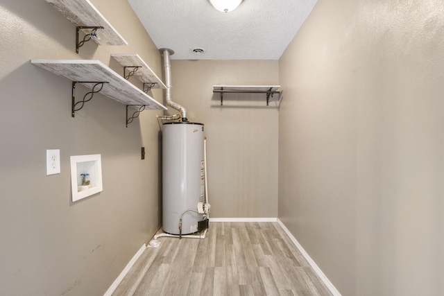 washroom with light wood-type flooring, a textured ceiling, hookup for a washing machine, and gas water heater