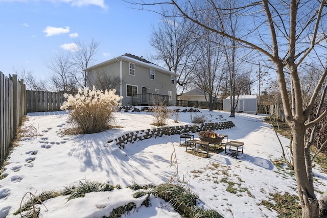 yard covered in snow with a storage shed and a fire pit