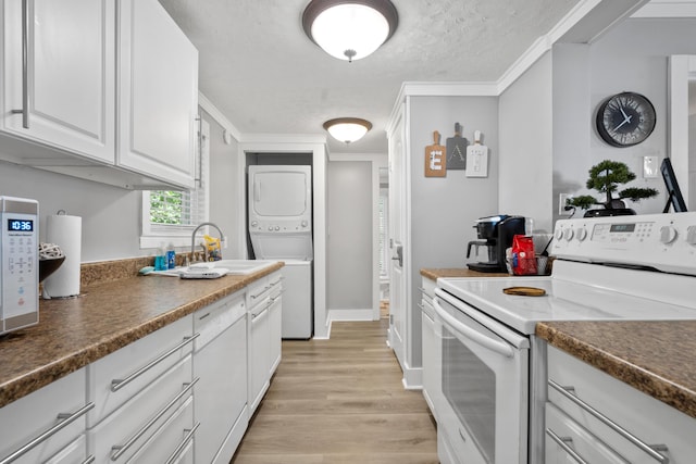 kitchen with white cabinets, sink, stacked washer and clothes dryer, ornamental molding, and electric range