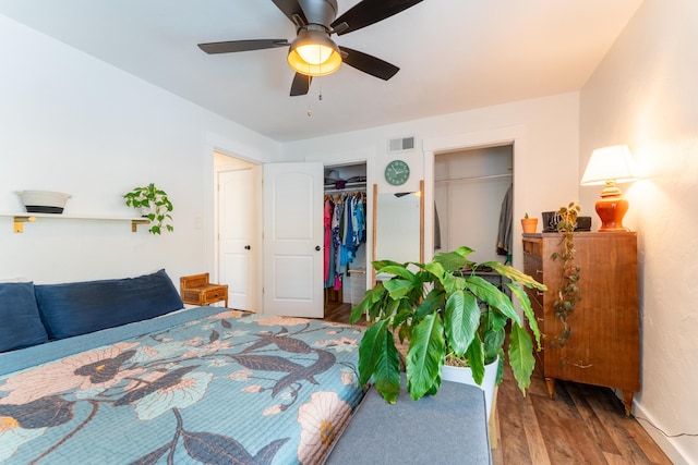 bedroom with ceiling fan, two closets, and hardwood / wood-style floors