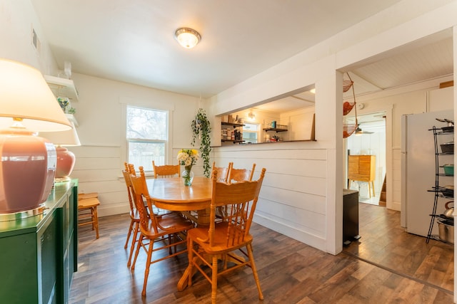 dining room featuring dark hardwood / wood-style floors and wood walls