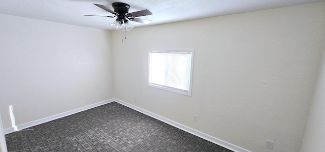 spare room featuring dark carpet and ceiling fan