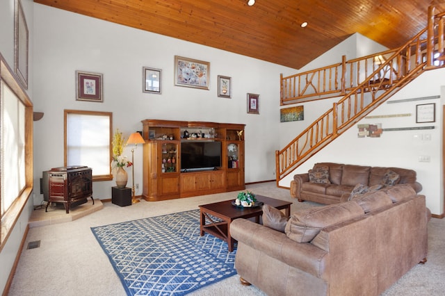 living room with high vaulted ceiling, wooden ceiling, a wood stove, and light carpet