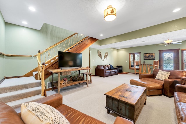 living room with light colored carpet, ceiling fan, and a textured ceiling