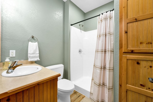 bathroom featuring toilet, hardwood / wood-style flooring, walk in shower, and vanity