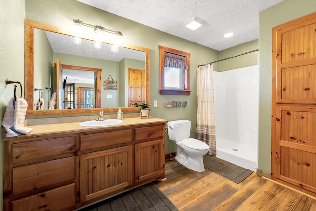 bathroom featuring curtained shower, a textured ceiling, hardwood / wood-style floors, toilet, and vanity