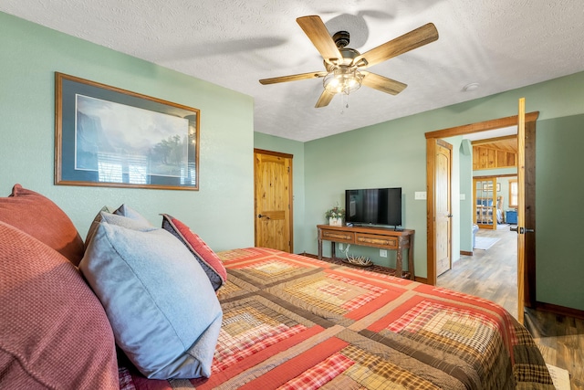 bedroom with a textured ceiling, ceiling fan, and hardwood / wood-style floors