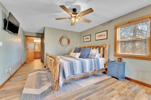 bedroom featuring ensuite bath, light wood-type flooring, ceiling fan, and a textured ceiling