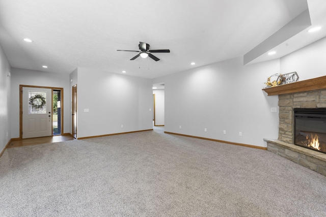 unfurnished living room featuring ceiling fan, a stone fireplace, and carpet flooring