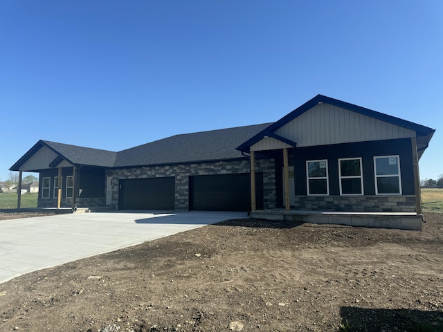 view of front of property with a porch, stone siding, a garage, driveway, and roof with shingles