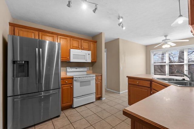 kitchen with white appliances, pendant lighting, light tile patterned flooring, and sink