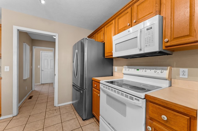 kitchen with white appliances, a textured ceiling, and light tile patterned floors