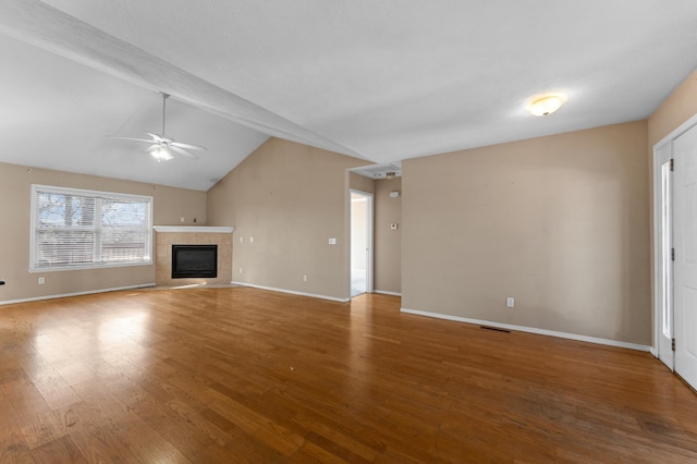 unfurnished living room with vaulted ceiling, a tile fireplace, ceiling fan, and hardwood / wood-style floors