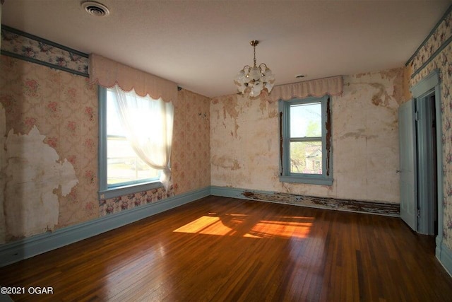 spare room with dark wood-type flooring and an inviting chandelier